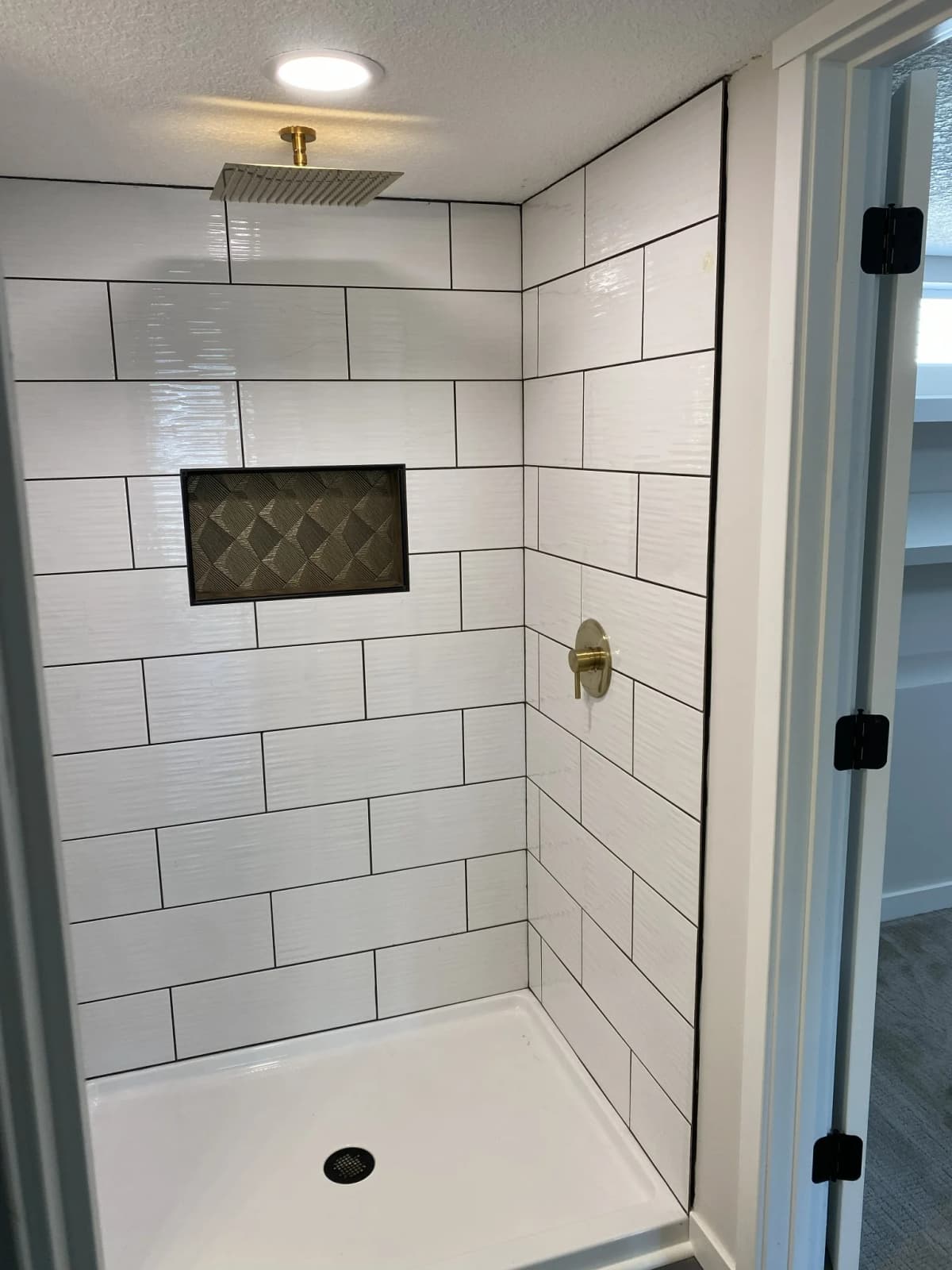 Walk-in shower with large white tile, a decorative recessed niche, and brass fixtures in East Bethel, MN
