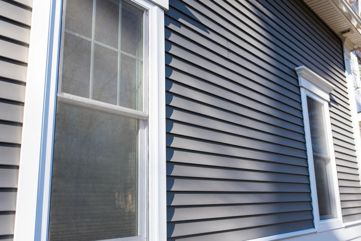 A double-hung replacement window framed by new navy siding on a Forest Lake, MN home