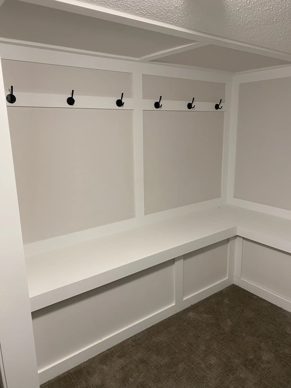 Built-in mudroom bench with paneled walls and a row of coat hooks in Wyoming, MN